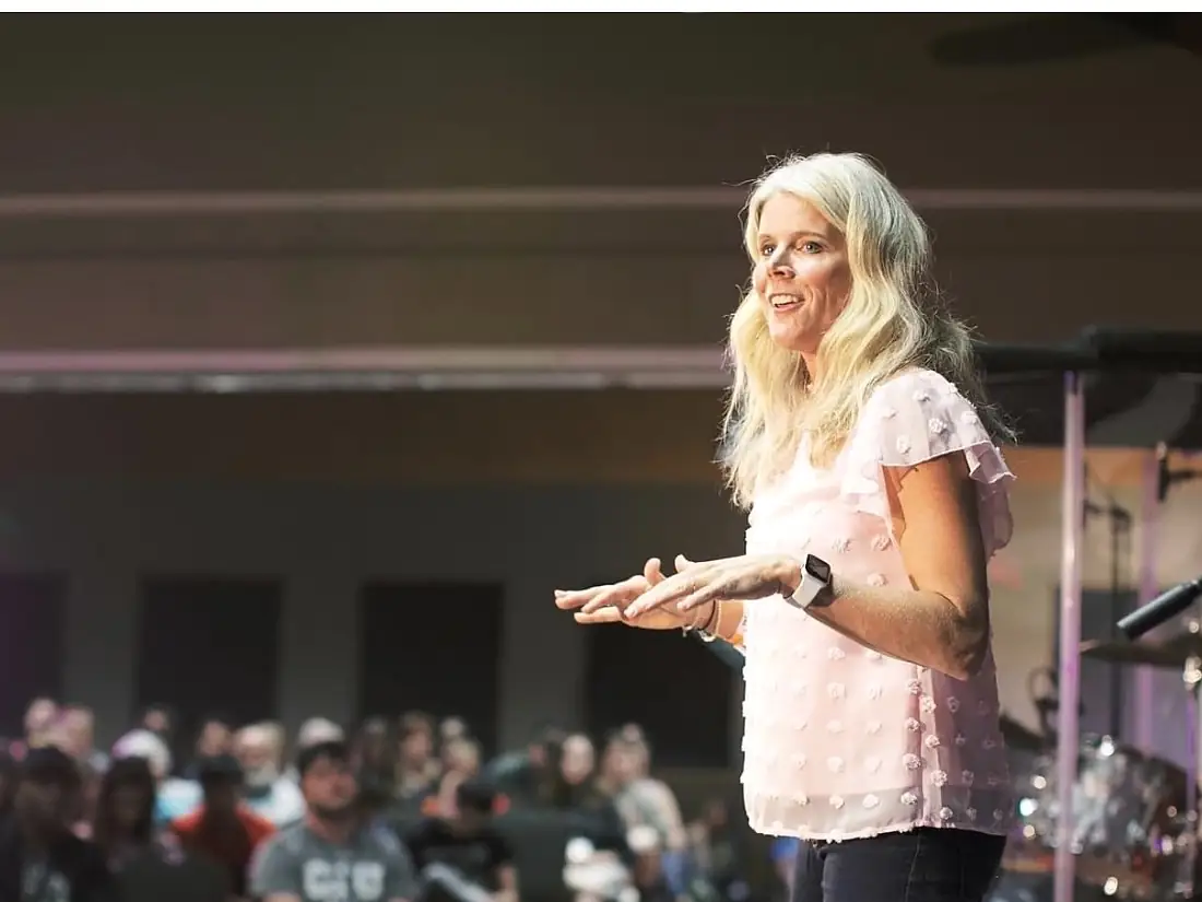 Sara speaking on stage in a pink shirt